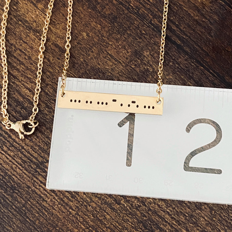 morse code sisters bar necklace on a ruler to show length at 1 3/8"