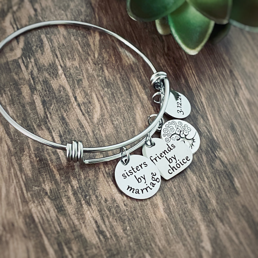 Silver Sister in Law  personalized charm bracelet with 4 charms. First charm is engraved with "sister by marriage". next is a tree of life symbol char. next is a heart charm engraved with "friends by choice" last charm is a round charm engraved with date "6.10.18"