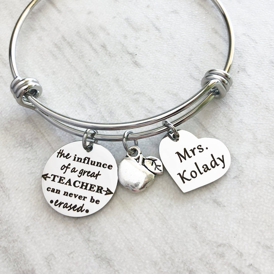 silver teacher bangle charm bracelet with engraved "the influence of a great teacher can never be erased" an apple charm and a 3/4" heart engraved with teachers name "mrs kolady""
