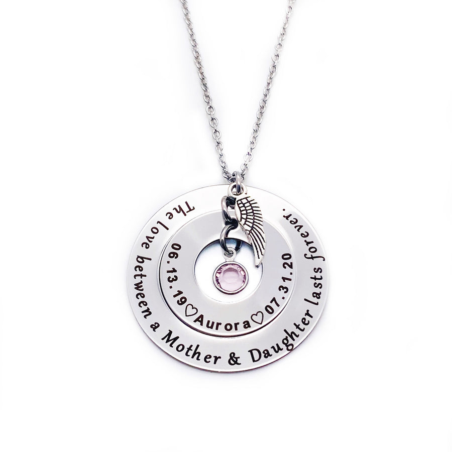Outer 1.25 inch silver hollow round disc engraved with "The love between a mother & daughter lasts forever" Small 1 inch hollow round disc engraved with 06.13.19 a outline of a heart the name Aurora outline of a heart and 07.31.20 A june pink birthstone dangling in the center. Angel wing is attached to the 2 disc hollow pendants and adorned with a stainless steel cable chain.