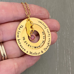 Yellow Gold Pendant necklace. engraved Outer 1.25 inch hollow round disc engraved with "The love between a mother & daughter lasts forever" Small 1 inch hollow round disc engraved with 10.21.51  a outline of a heart the name Mom outline of a heart and 10.13.20. A pink octoberl birthstone dangling in the center. Angel wing is attached to the 2 disc hollow pendants and adorned with a stainless steel cable chain.
