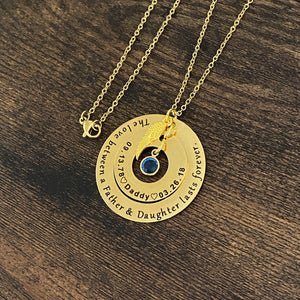 engraved yellow gold memorial necklace engraved with "The love between a father and daughter lasts forever" and personalized with date of birth 9.13.78, Daddy, and heaven date 3.26.18" and a blue september birthstone and angel wing charm. pendant attached to a cable chain