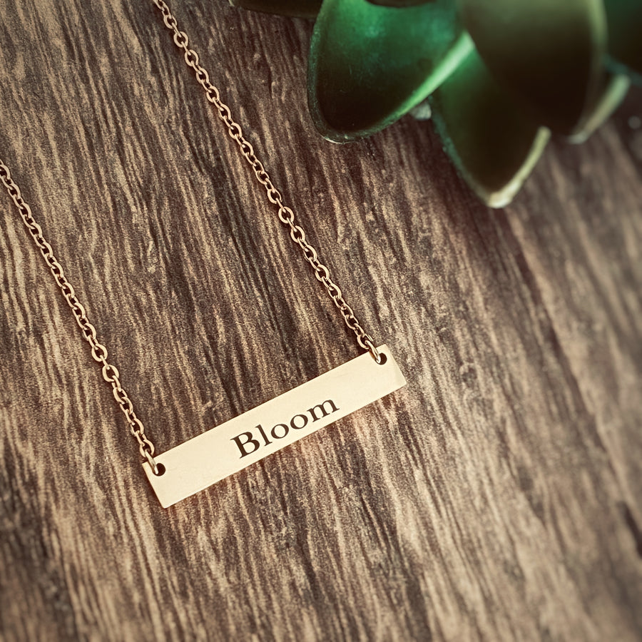 Word "Bloom" engraved on a Rose Gold bar necklace. Word of the year