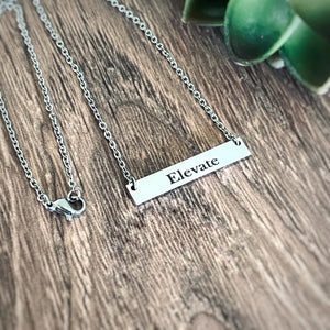 Word "Elevate" engraved on a silver bar necklace. Word of the year