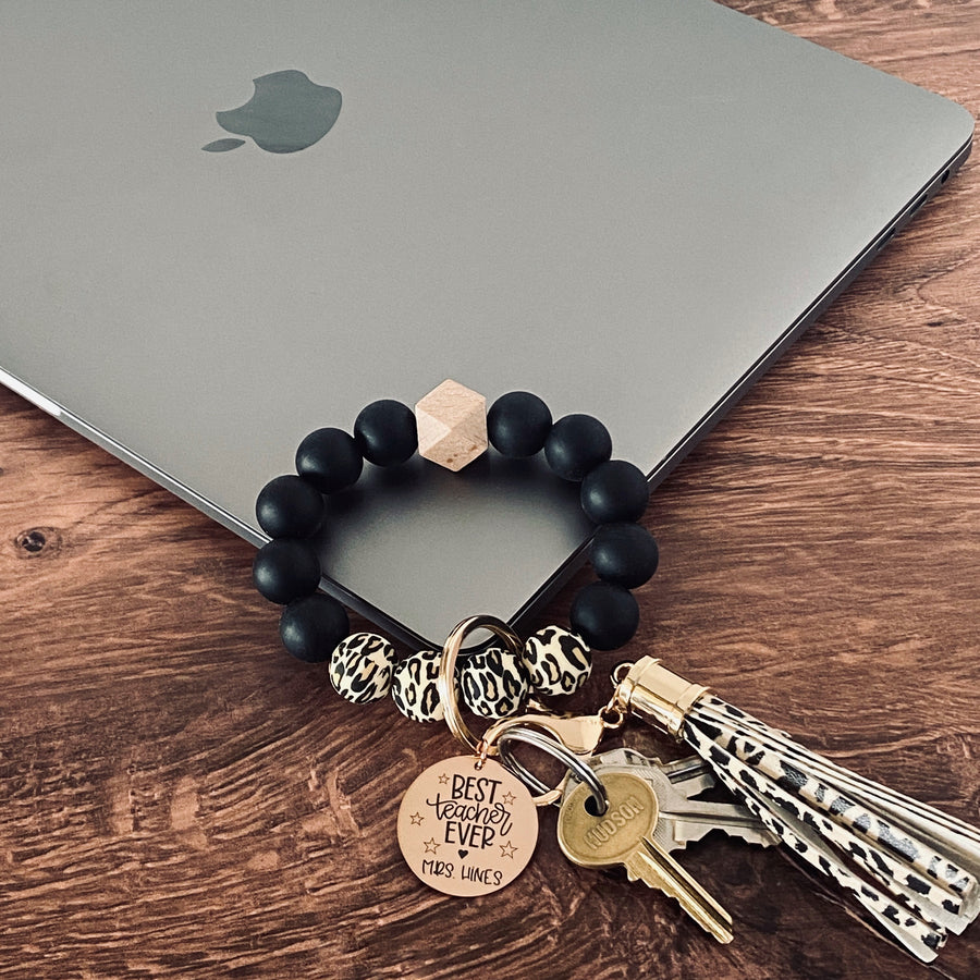 cheetah print and black silicone beaded wristlet with tassel and charm tag engraved with "best teacher ever" and stars and the name Mrs. Hines.