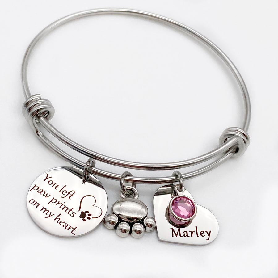 silver triple loop stainless steel hypo-allergenic bangle charm bracelet with engraved disc "you left paw prints on my heart" a dog paw charm and an engraved heart name tag with dog's name and birthstone