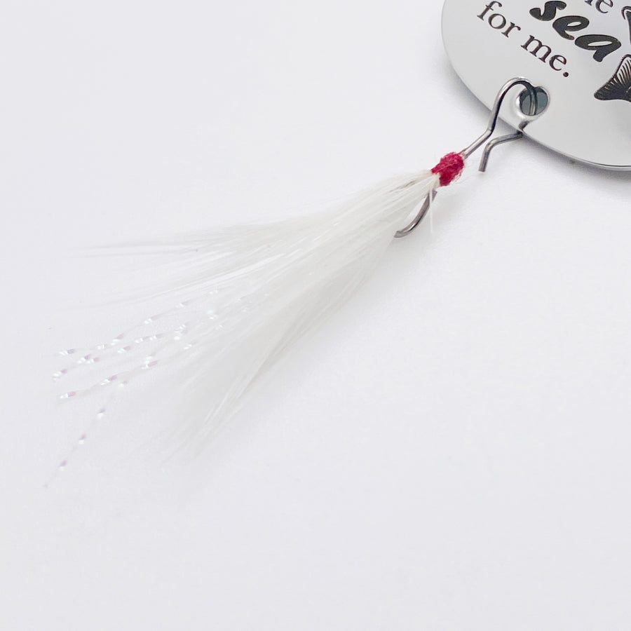 silver and white shiny fishing feather attached to the bottom of the lure