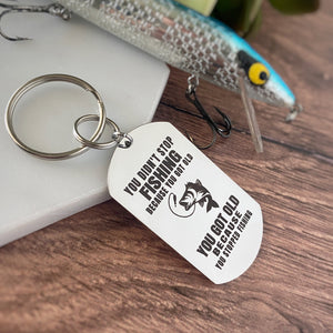 Silver stainless steel dog tag keychain engraved with the phrase, "you didn't stop fishing because you got old. You got old because you stopped fishing"