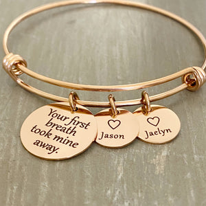 stainless steel rose gold bangle charm bracelet with a 3/4 inch disc engraved with "your first breath took mine away". 1/2 inch name discs with open heart image above the engraved name. 