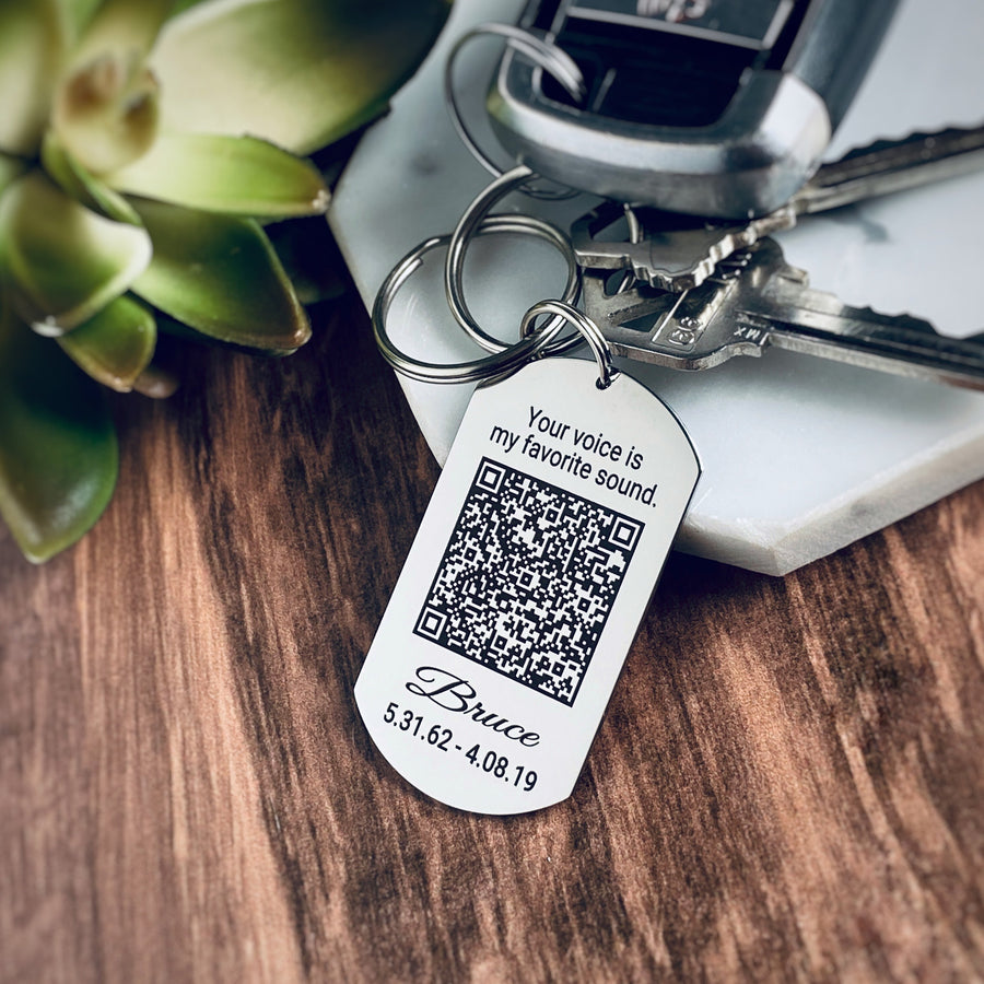 silver stainless steel dog tag keychain engraved with the phrase Your voice is my favorite sound. Then a voicemail QR code. Underneath the qr code is the name Bruce, date of birth 5.31.62, and death date 4.08.19.