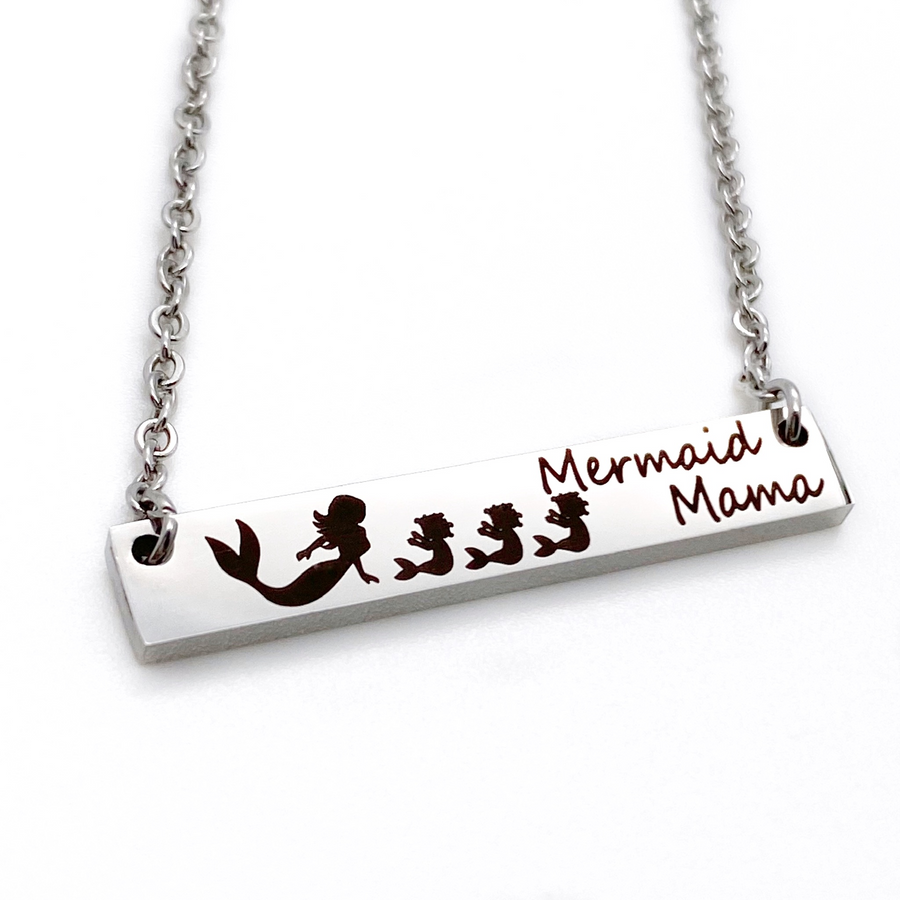 engraved 1.2-inch by .25 inch bar necklace in silver gold or rose gold and engraved with a mom mermaid image and your choice of mermaid babies. Engraved with the verbiage "mermaid mama"